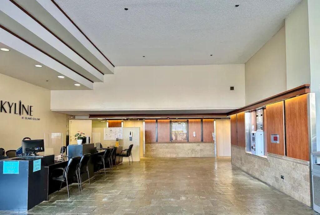 A spacious lobby with a reception desk, seating area, and a view of the island colony.