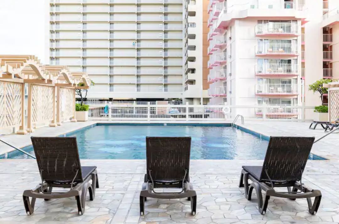 Un espace piscine comprenant trois chaises longues et une piscine.