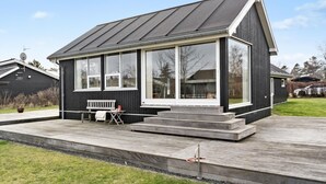 A modern black house with a large glass window, a wooden deck, and a bench. - Cozy home in Odder with WiFi (Odder)