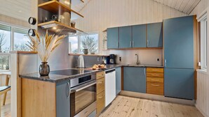 A modern kitchen with wooden cabinets, a built-in oven, and a large window. - Cozy home in Odder with WiFi (Odder)