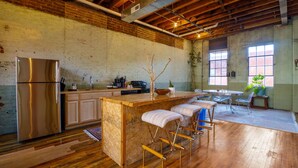 A spacious kitchen with a wooden island, stainless steel refrigerator, and bar stools. - Downtown Lynchburg *REAL loft living* Va Virginia (Lynchburg)