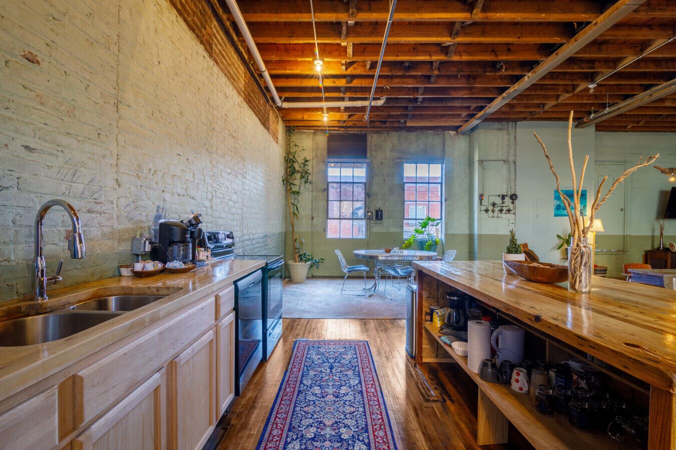 Una cocina rústica con vigas de madera, un ventanal grande y un comedor con sillas y una mesa.