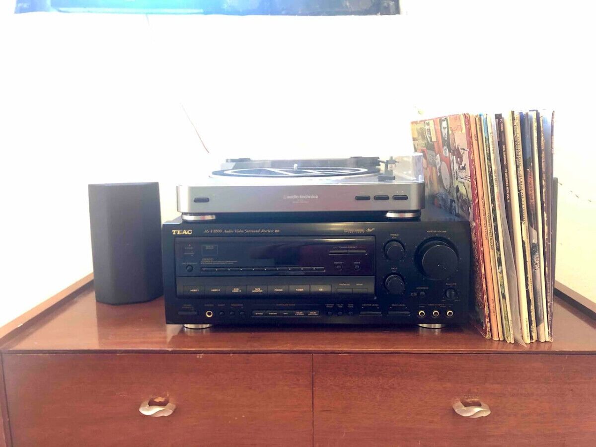A TEAC audio system on a wooden cabinet with a stack of CDs to its right.