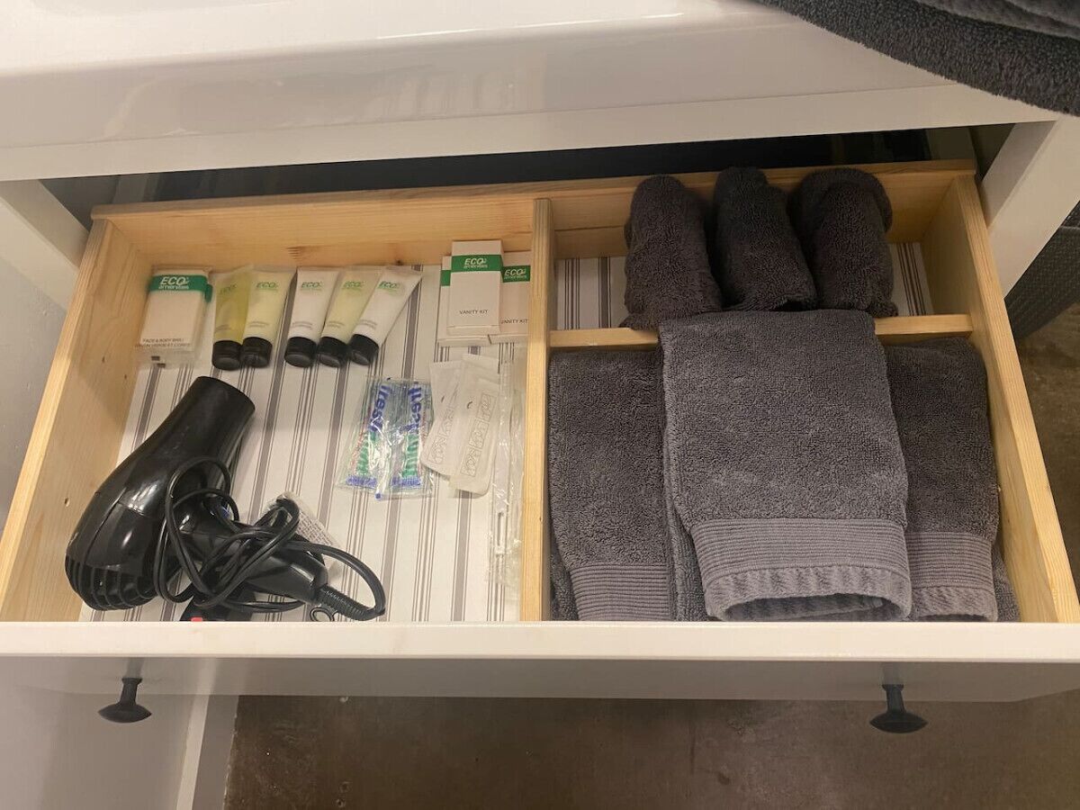 A drawer with neatly organized items including hair care products, a hairdryer, and folded towels.