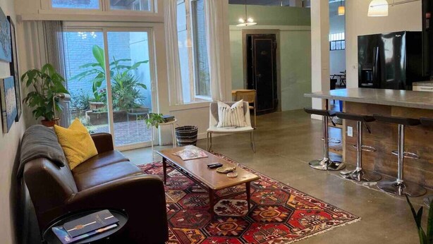 Un salon moderne comprenant un canapé, une table basse et un coin bar avec des tabourets.