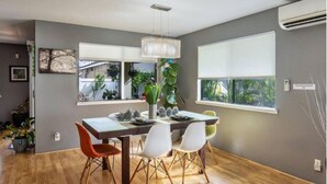 A dining area with a wooden table, white chairs, and a hanging light fixture. - Welcome to Ho'onani Pua Hale (Waipahu)