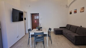 A modern living room with a dining table, chairs, a sofa, and a flat-screen TV mounted on the wall. - DOMVS Ginori,Testaccio (Roma)
