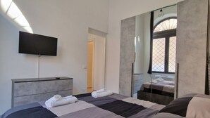 A modern hotel room with a large bed, a flat-screen TV mounted on the wall, and a large mirror reflecting the room. - DOMVS Ginori,Testaccio (Roma)