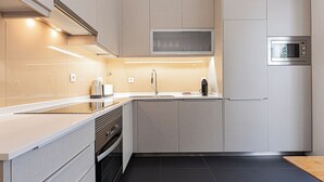 A modern kitchen with a built-in microwave, stainless steel appliances, and a sleek countertop design. - Cortes Apartment in Lisbon Historic (Lisbon)