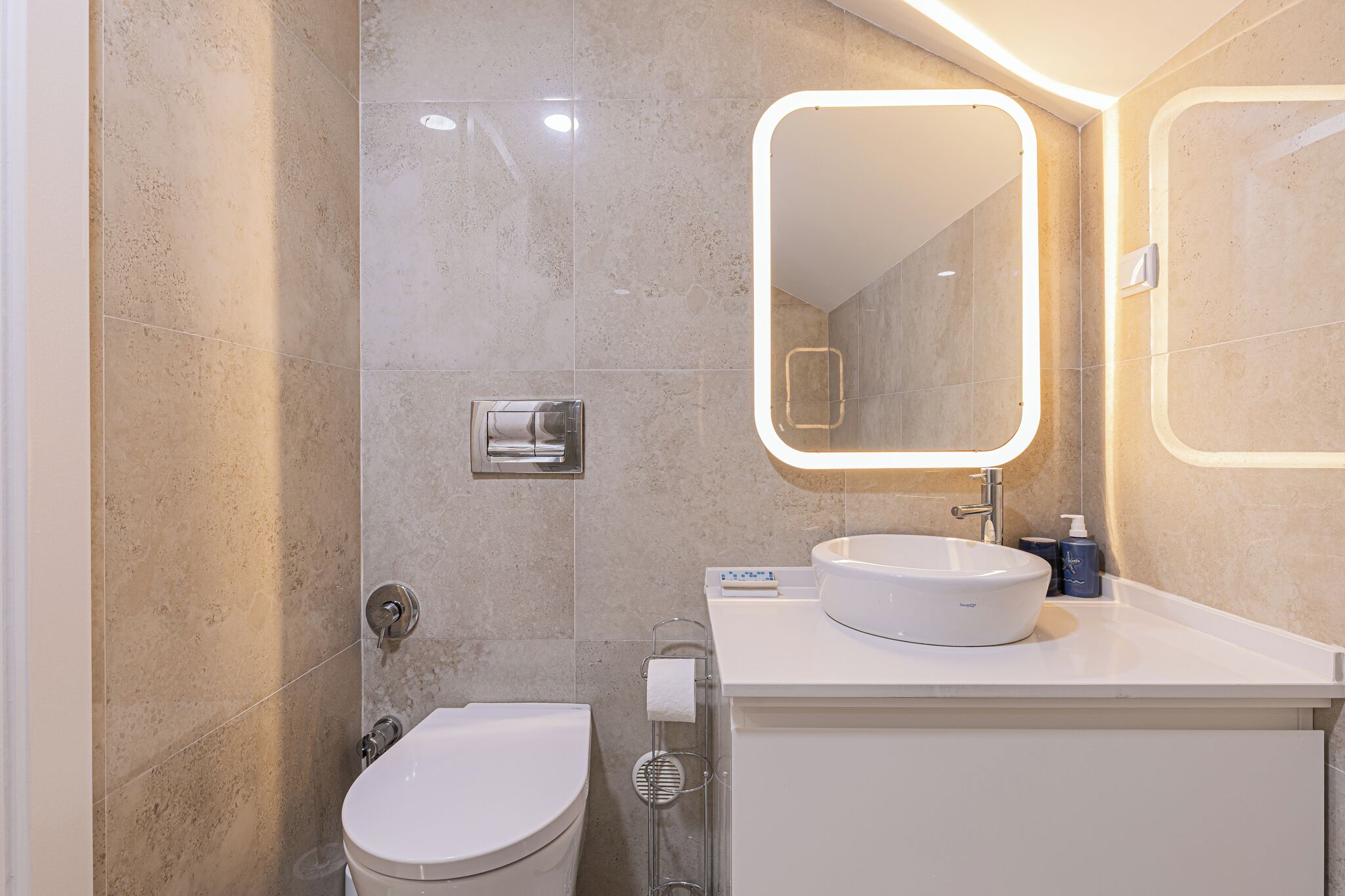 A modern bathroom with a toilet, sink, and mirror.