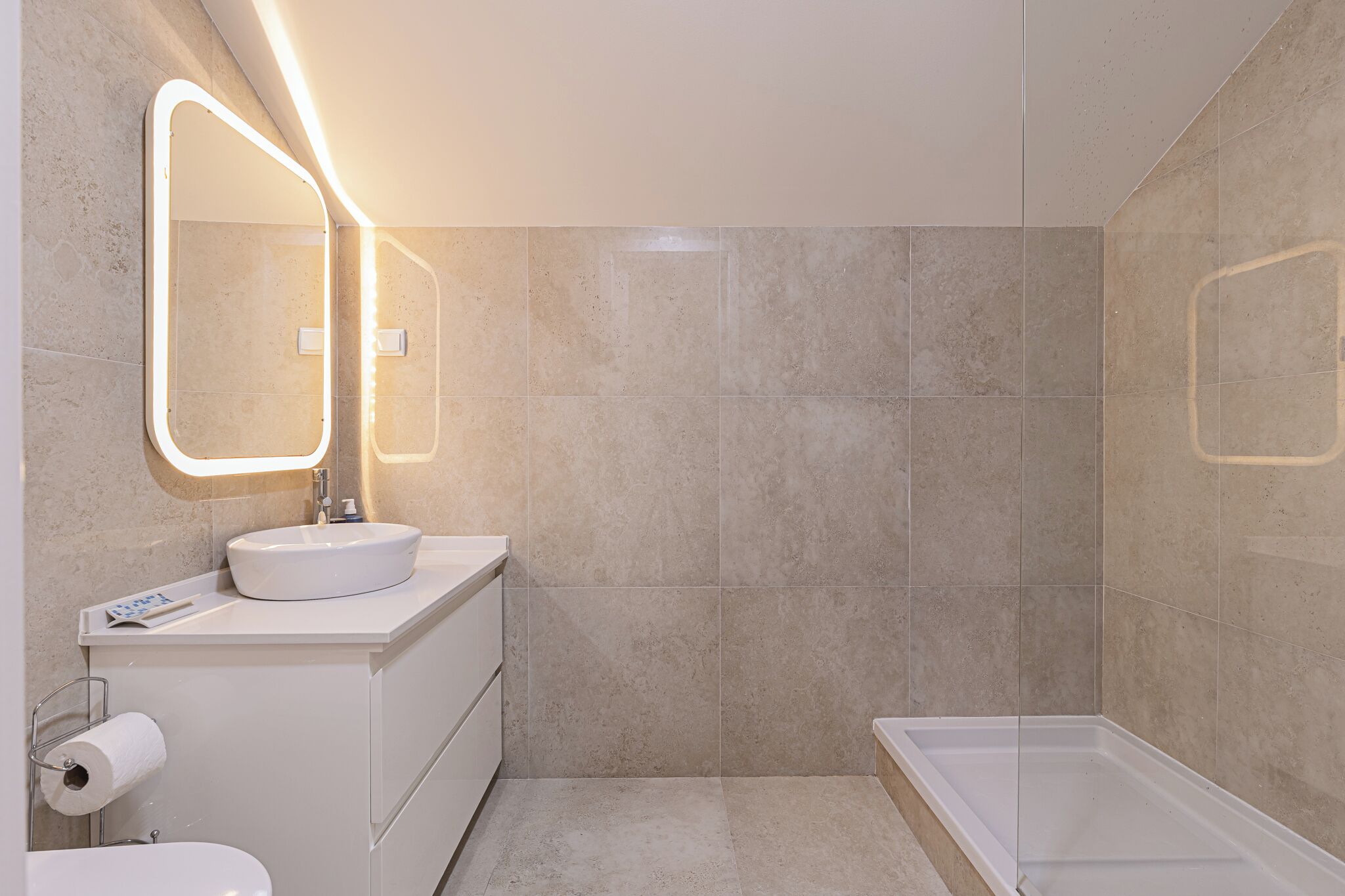 A bathroom with a white sink, a mirror with lights, a toilet, and a bathtub.