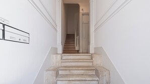 A staircase with a handrail, a door at the top, and a wall-mounted light switch. - Cortes Apartment in Lisbon Historic (Lisbon)