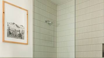 A modern bathroom with a toilet, a shower with a glass door, and a framed picture on the wall.