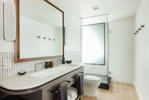 A modern bathroom with a large mirror, white sink, and a glass shower enclosure.