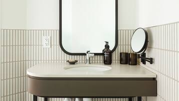 A bathroom with a white sink, black pipes, and a mirror.