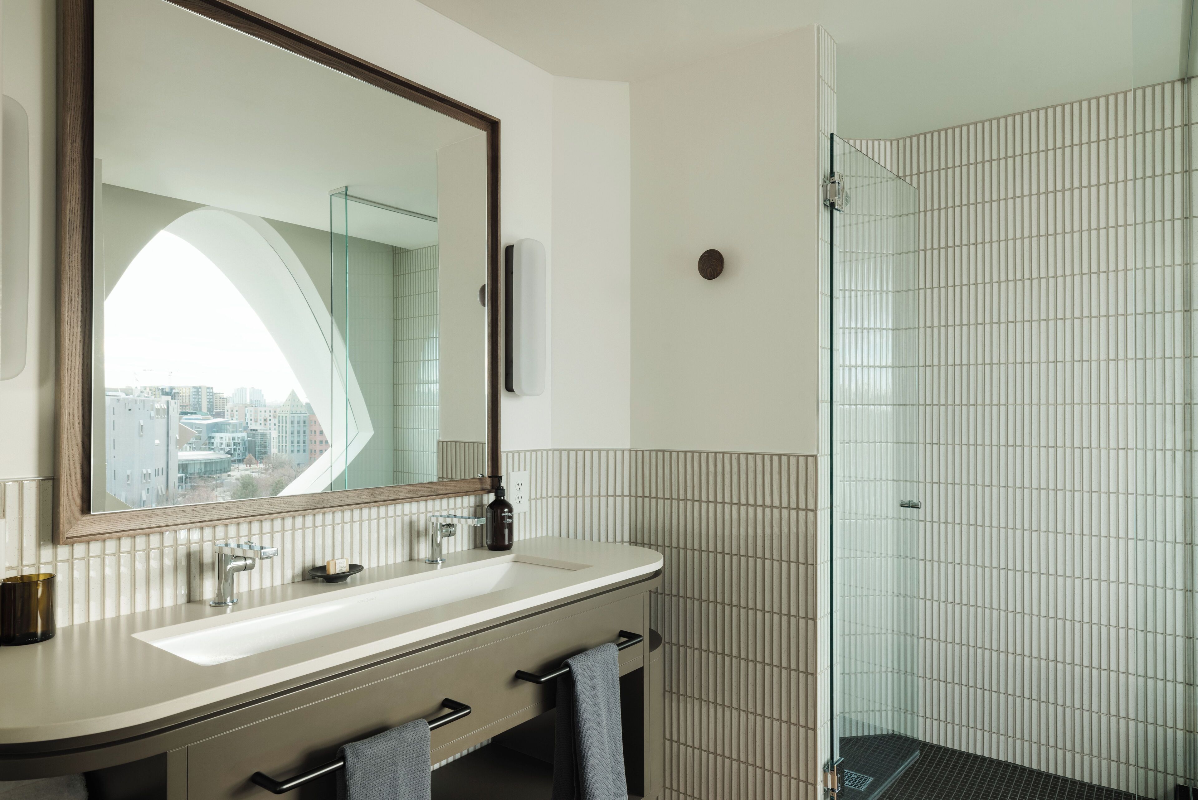 A modern bathroom with a large mirror, a sink, and a glass shower enclosure.