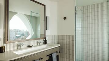 A modern bathroom with a large mirror, a sink, and a glass shower enclosure.