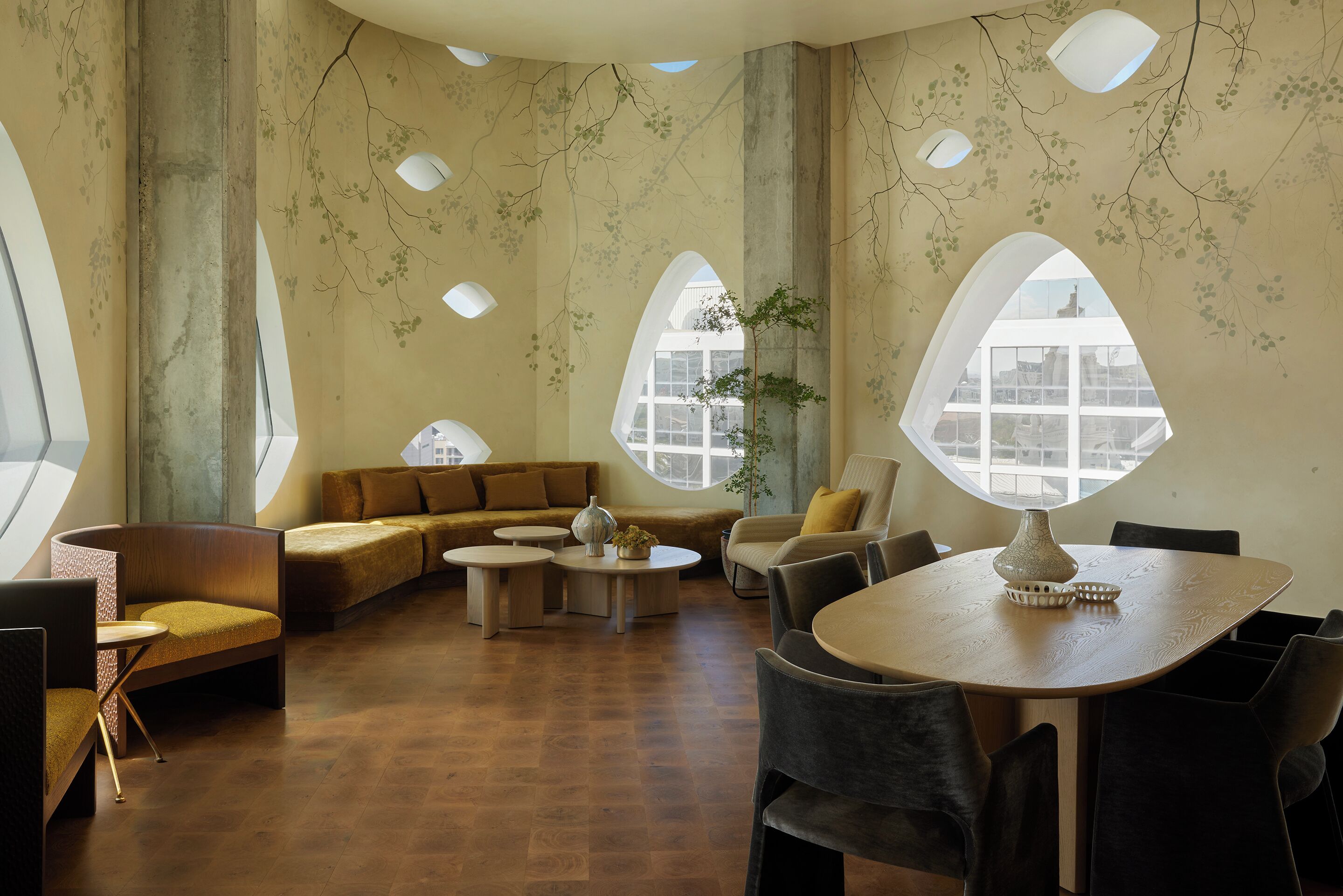 Un intérieur moderne avec un plafond incurvé, de grandes fenêtres et un espace salon central doté d’une table ronde.