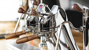 A close-up of espresso machine handles with wooden grips and digital displays.