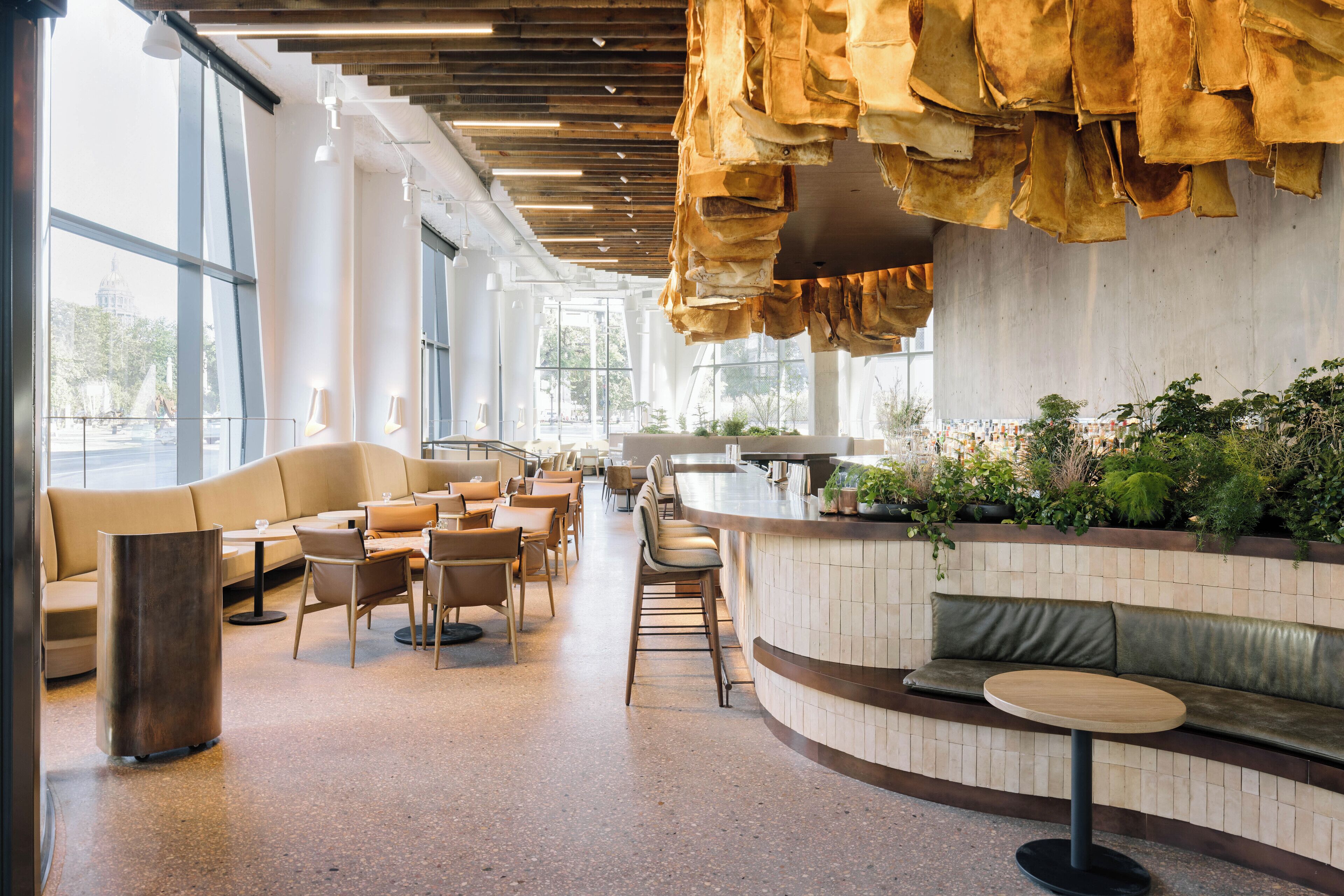 A modern restaurant with a curved counter, seating area, and large windows.