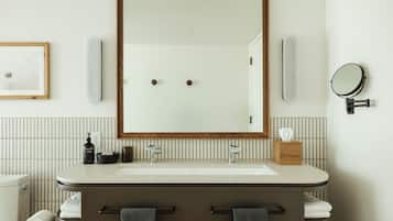 Uma casa de banho moderna com um espelho grande, duas bacias, uma sanita e um porta-toalhas.