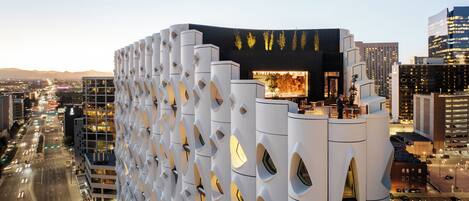 Un edificio moderno con una fachada distintiva que presenta cortes geométricos y una entrada destacada con un amplio ventanal.