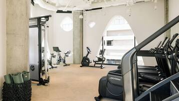 A gym with exercise equipment, a large window, and a concrete pillar.