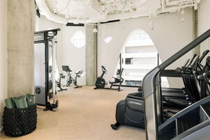 A gym with exercise equipment, a large window, and a concrete pillar.