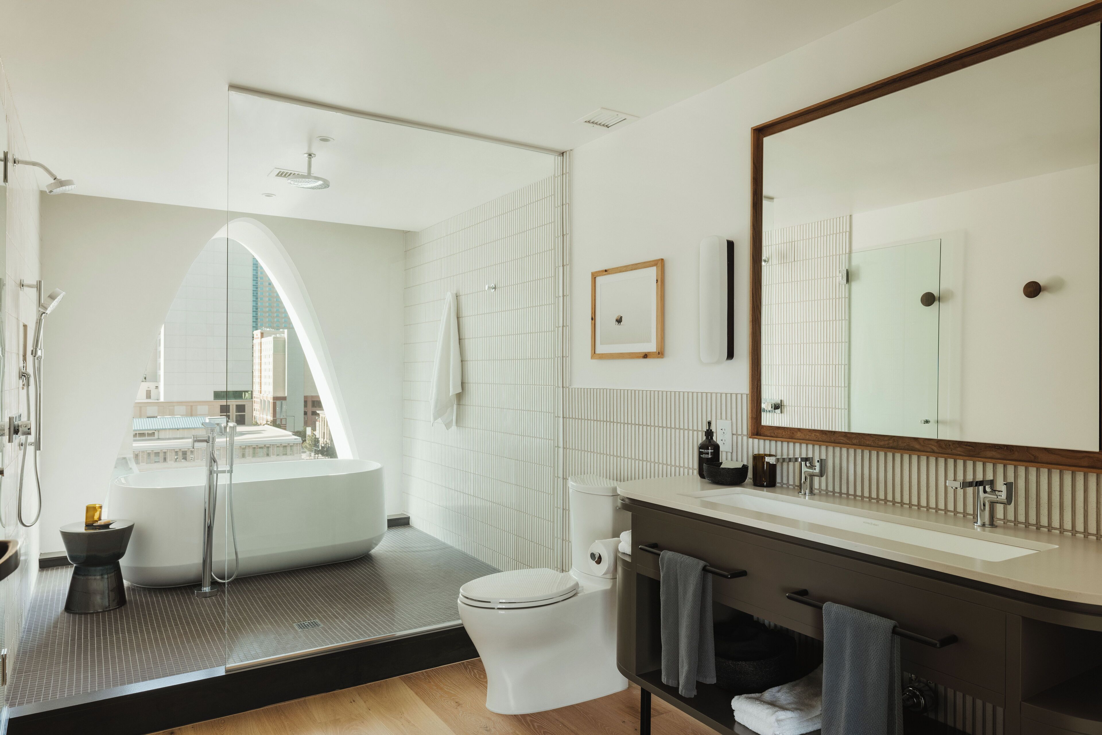 A modern bathroom with a large bathtub, a toilet, and a vanity with a mirror.