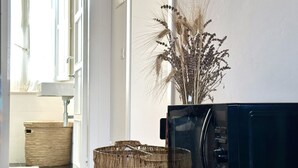 Une cuisine équipée d’un four à micro-ondes, de paniers en osier et d’un vase contenant des plantes séchées.