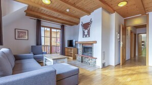 A living room with a sofa, a television, a fireplace, and a wooden ceiling. - Stunning apartment in Pohorje with WiFi (Pohorje)