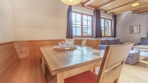 A wooden dining table with chairs, a tray with glasses, and a window with curtains. - Stunning apartment in Pohorje with WiFi (Pohorje)