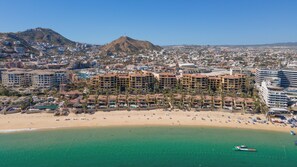 A coastal resort with beachfront villas, a marina, and a mountain backdrop.