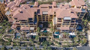 Un hôtel de grande hauteur doté de nombreux balcons, d’une cour intérieure avec une piscine et entouré de palmiers.