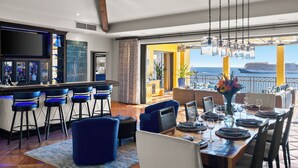 Un espace repas avec vue sur la mer, un bar avec des tabourets et une grande fenêtre.