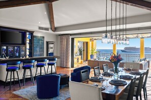 Un espace repas avec vue sur la mer, un bar avec des tabourets et une grande fenêtre.