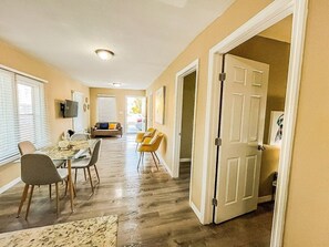 Amplia sala de estar con una mesa y sillas para comer, un sofá y una puerta que da a otra habitación.