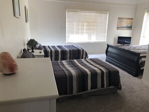 A bedroom with two beds, a desk, a lamp, a television, and a painting on the wall. - 2 master suites plus kitchenette in upper level of our townhome  (Mesa)
