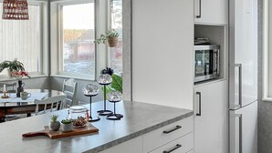 Eine moderne Küche mit weißen Schränken, einer Marmorarbeitsplatte und einer eingebauten Mikrowelle.