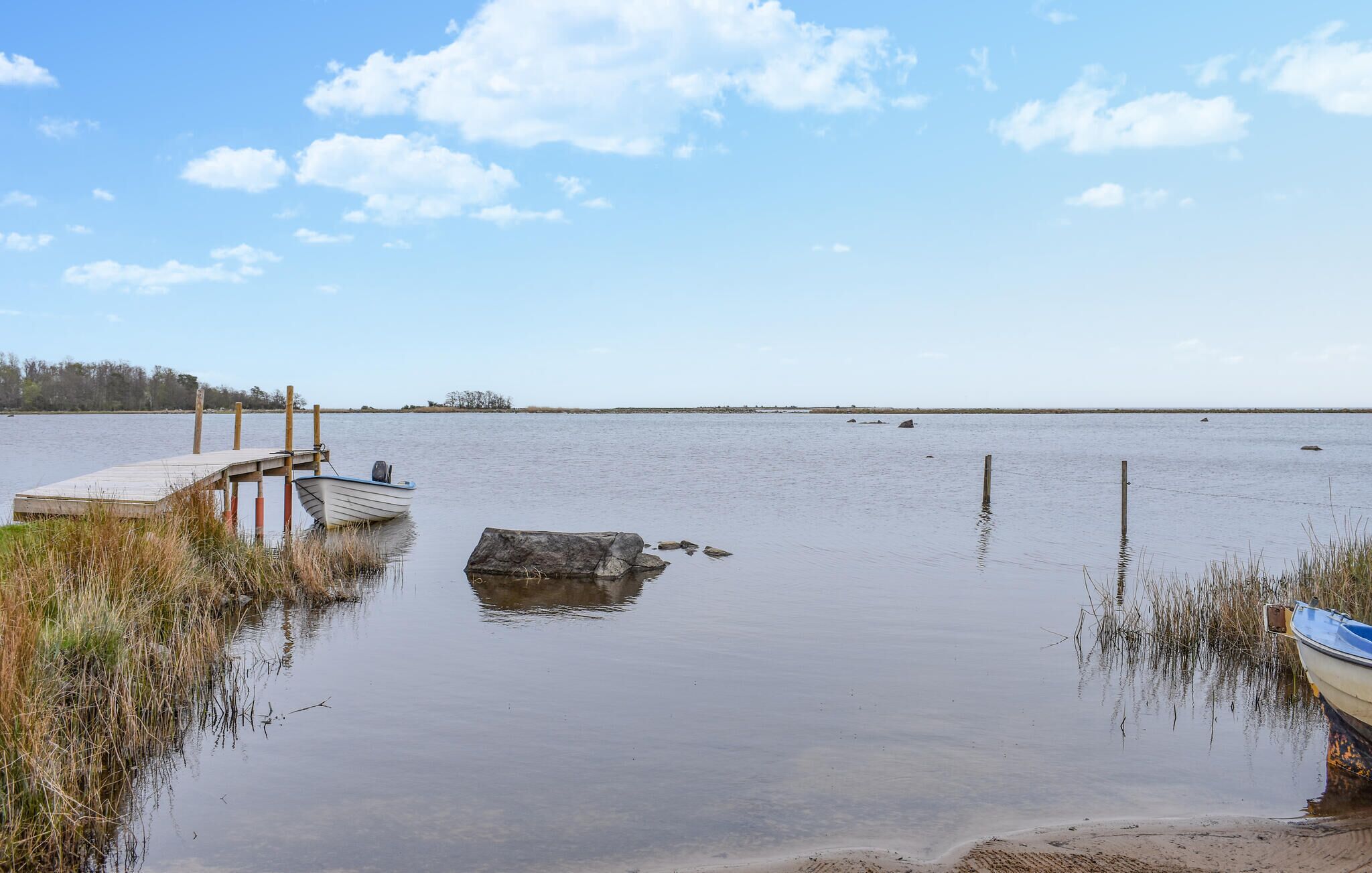 A calm lake with a wooden dock and a small boat.