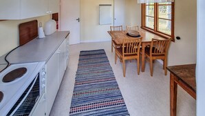 A compact kitchen with a stove, a dining table with chairs, and a window with curtains.