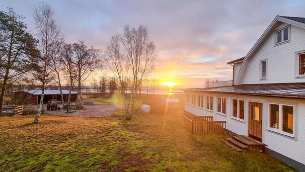 A house with a wooden deck and a view of the sunset.
