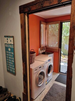 Un cuarto de lavado con lavadora, un lavamanos y un ventanal con cortinas.