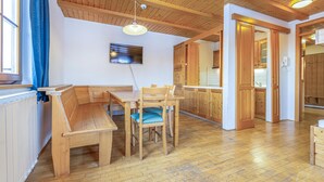 A wooden dining area with a bench and table, wooden cabinets, and a television mounted on the wall. - Beautiful apartment in Pohorje (Pohorje)