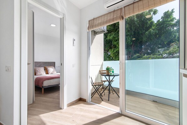Una habitación con una cama, una mesa con sillas y un ventanal corredero que da a un espacio al aire libre.