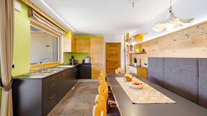 A modern kitchen with a dining area, wooden cabinets, and a long table.