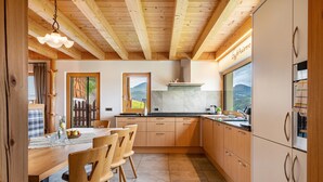 Una cocina moderna con armarios de madera, un comedor con mesa y sillas, y vista al exterior.