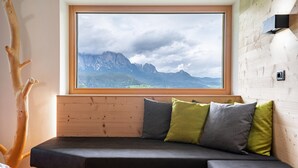 Una cabaña de madera con una cama empotrada, una ventana con vistas a la montaña y una pared de madera.