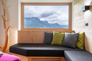 A wooden cabin with a built-in bed, a window with a mountain view, and a wooden wall.