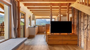 Una cocina moderna con vigas de madera, un ventanal y vistas a montañas.